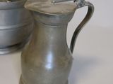 a silver pitcher and a silver pot on a white table