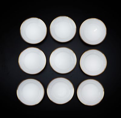 six bols blancs aux bords dorés posés sur un fond noir