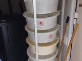 a tall stack of buckets and a broom in the corner of a room