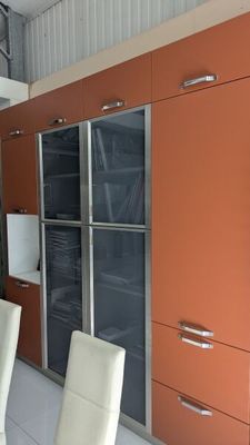 salle à manger avec des placards orange, des chaises blanches et un sol en carrelage blanc