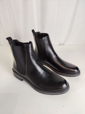 une paire de bottines Chelsea en cuir noir sur fond blanc