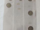 five coins in a clear plastic bag on a white surface