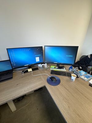 a desk with three monitors and a laptop on it