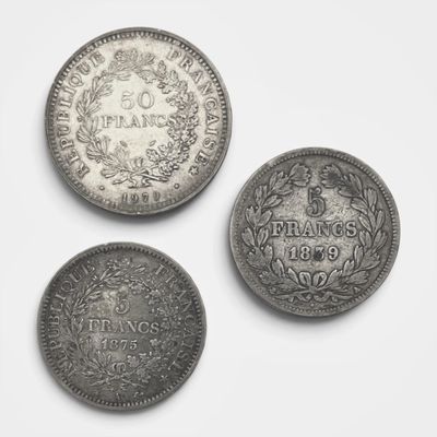 trois types différents de pièces d'argent sur une surface blanche