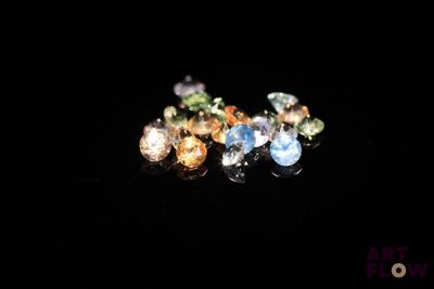 un gros plan sur un assortiment de pierres précieuses de différentes couleurs posées sur une surface noire