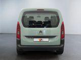 the back of a small green van parked in a room