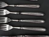 five forks and a knife on a black surface