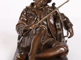 statue en bronze représentant un garçon assis sur un rocher, un violon à la main
