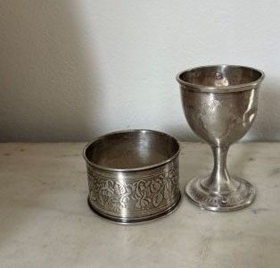 a silver cup sitting next to a silver cup on a table
