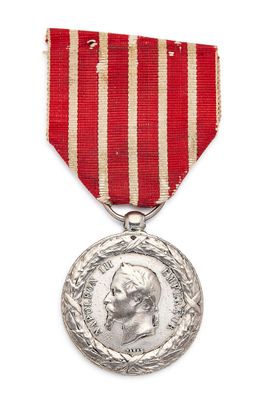 Gros plan sur une médaille sur fond blanc, accompagnée d'un ruban rouge