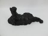 sculpture of a black dog laying down on a white surface