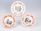 three plates with red and white designs on them sitting on a white surface