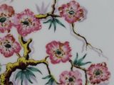 a plate with a painting of a tree and flowers on it