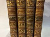 five old books are stacked on top of each other on a white surface