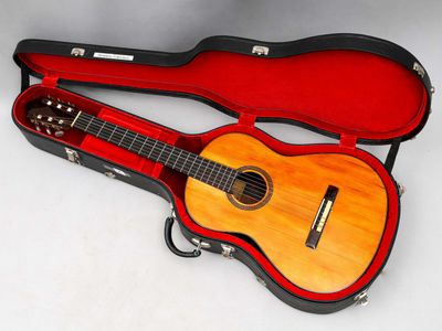 une guitare dans un étui, posée sur une surface blanche