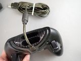 a person holding a video game controller with a cord attached to it