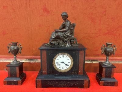 une statue de femme assise sur une table à côté de trois vases et d'une horloge