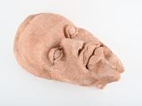 une sculpture en argile représentant le visage d'un homme sur une surface blanche