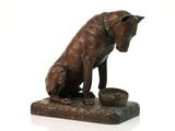 statue en bronze représentant un chien avec un bol de nourriture posé sur une surface blanche