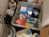 a bin full of cleaning supplies in the corner of a bathroom
