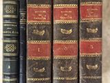 three old books sitting on top of a table next to each other