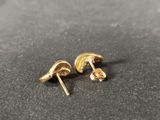 a pair of gold stud earrings sitting on top of a black surface