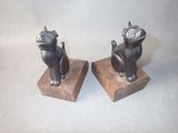 two statues of cats sitting on a wooden block