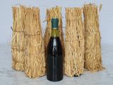 a bottle of wine sitting next to a bunch of straw