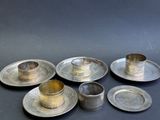 six assiettes et tasses plaquées argent sur un fond noir