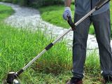 Cet homme utilise une débroussailleuse pour tondre l'herbe.
