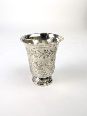 une tasse en argent posée sur une surface blanche