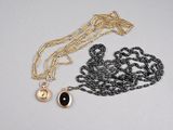 une chaîne en or avec une perle noire et un collier en or orné d'une perle noire