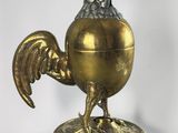 a gold colored chicken on a stand with a red eye
