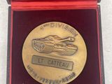 gold medal with a tank on it sitting in a red box