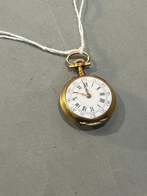 une montre de poche en or suspendue à un cordon sur une table