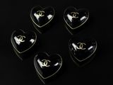 four heart shaped black and gold chandelier buttons on a black background