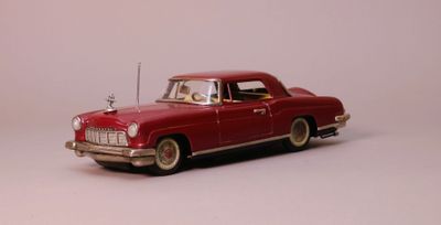une petite voiture rouge posée sur une surface blanche