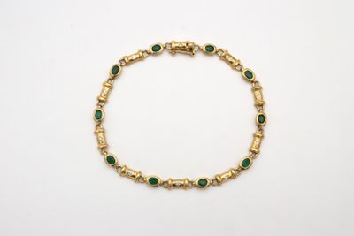 un bracelet en or orné d'émeraudes sur fond blanc