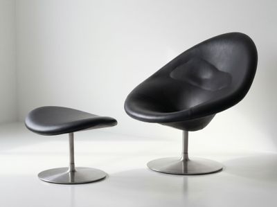 une chaise noire et un pouf noir dans une pièce blanche
