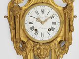 a gold clock on the wall with roman numerals on it