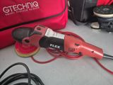 a red electric sander sitting on a table next to a red bag