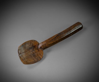 an old wooden spatula with a wooden handle on a gray surface