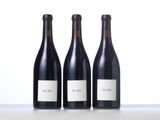 three bottles of red wine are lined up on a table