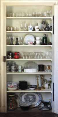 Il y a beaucoup de vaisselle et de verres sur les étagères de cette cuisine