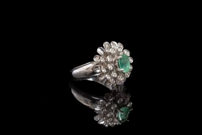 une bague en émeraude et diamant sur une surface noire