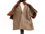 une poupée vêtue d'un manteau marron et d'un chapeau marron, posée sur un mannequin