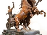a bronze statue of a man riding a horse and a man on a cart