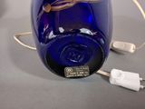 an image of a blue glass bottle with a cord plugged into it