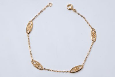 a gold bracelet with a leaf design on a chain