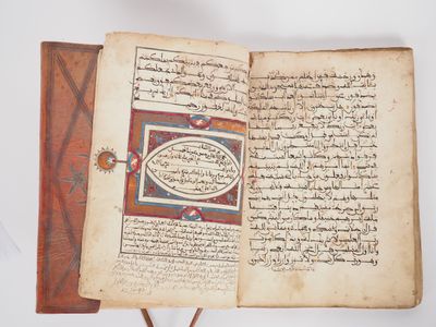 an open book with arabic writing on it sitting on a wooden stand